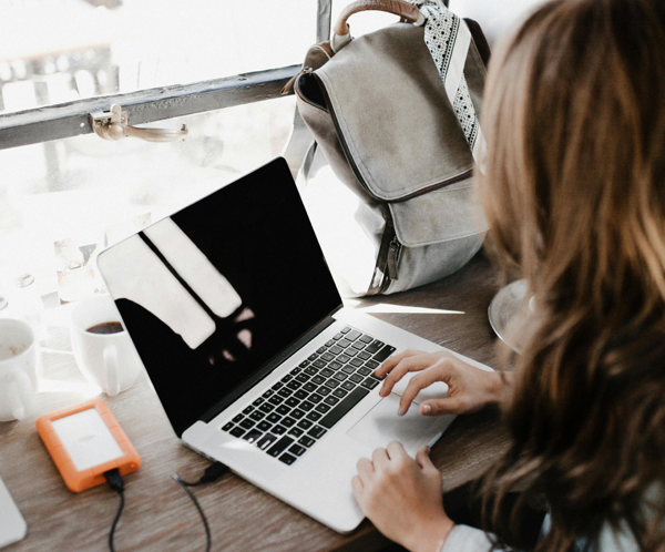 Close-up Photography of Woman Sitting Beside Table While Using Macbook